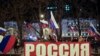 Gente ondea banderas nacionales rusas para celebrar, en el centro de Donetsk, el territorio controlado por militantes prorrusos, en el este de Ucrania, el lunes 21 de febrero de 2022 por la noche.