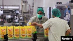 Pekerja mengeluarkan paket minyak goreng untuk pengemasan akhir di gudang milik Sinar Mas Agro Resources and Technology (SMART) di Marunda, Jawa Barat. (Foto: Reuters)