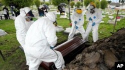 Trabajadores funerarios levantan un ataúd que contiene los restos de un hombre que murió de COVID-19, en el Cementerio Parque Zipaquirá en Zipaquirá, Colombia, el viernes 18 de junio de 2021