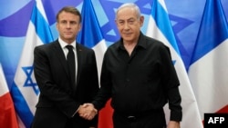 El presidente de Francia, Emmanuel Macron (izq), estrecha la mano del primer ministro israelí, Benjamín Netanyahu (der) durante una visita a israel el 24 de octubre de 2023.