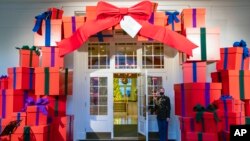 Un miembro de la Marina en la Casa Blanca sostiene la puerta de la entrada del ala este de la sede de gobierno en Washington DC durante una vista previa para la prensa de las decoraciones navideñas, el 29 de noviembre de 2021. 