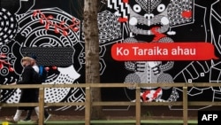 FILE - People walk past Maori language signs in Wellington, New Zealand, Sept. 13, 2018.