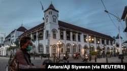 Seorang tukang becak bermasker duduk menunggu pelanggan di lokasi wisata Kota Tua, Semarang, Jawa Tengah, 1 Juli 2021. (Foto: Antara/Aji Styawan via REUTERS)