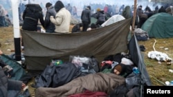 A migrant man sleeps in a camp near Bruzgi-Kuznica checkpoint on the Belarusian-Polish border in the Grodno region, Belarus, Nov. 18, 2021.