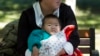 FILE - A child is wrapped up against the cold at a park in Beijing, China, Friday, Oct. 30, 2015. 