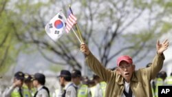 Anti-North Korea protester shouts as he holds the US and South Korean flags during a rally denouncing the North's recent announcement in Seoul, South Korea, April 24, 2012.