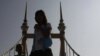 Cambodians walk Wednesday on a bridge on which hundreds of people stampeded during a water festival on Nov. 22. Monks prayed for happiness and safety Wednesday at a ceremony to reopen the bridge where at least 353 revelers were trampled to death in the ri