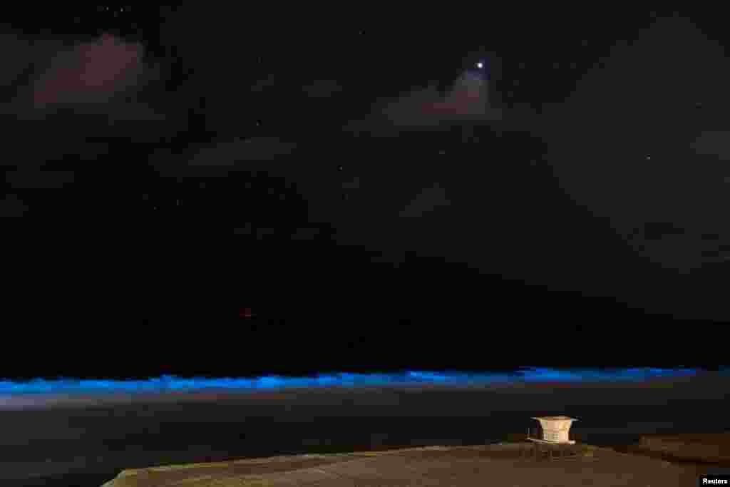 Bioluminescent algae glows in the crashing waves as a lifeguard tower sits on an empty beach during the outbreak of the coronavirus disease (COVID-19) in Encinitas, California, April 18, 2020.