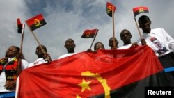 FILE - Resident students from Angola wave national flags as former Angolan President Jose Eduardo dos Santos's motorcade drives past after his arrival at Havana's Jose Marti airport September 20, 2007.