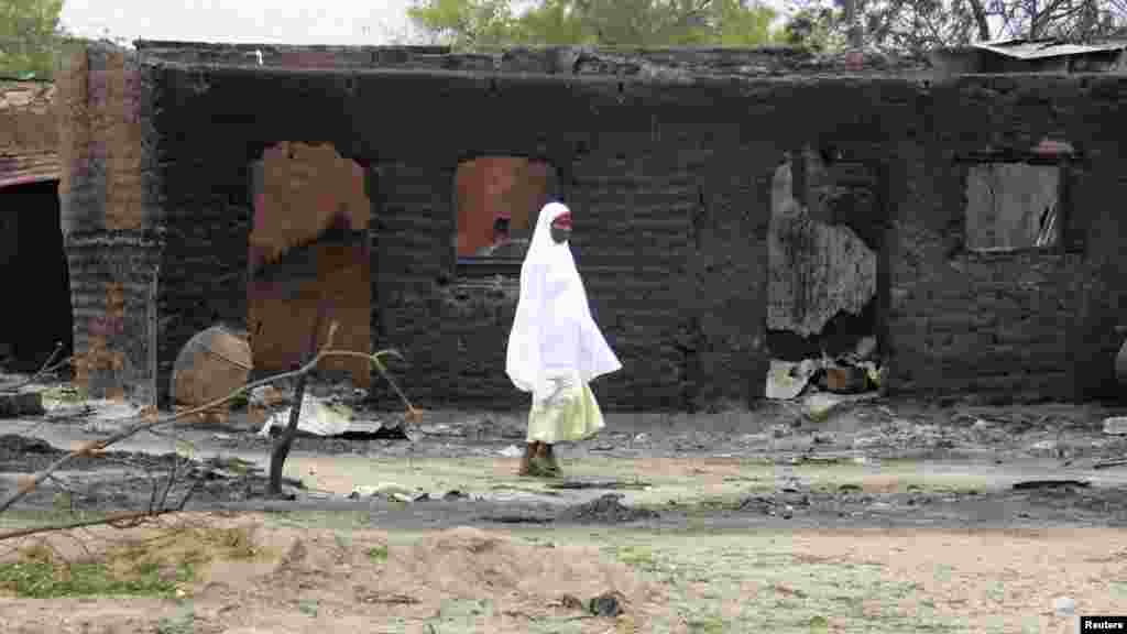 A woman walks past burnt houses in the aftermath of what Nigerian authorities said was heavy fighting between security forces and Islamist militants in Baga