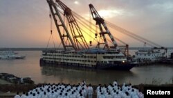 Para petugas penyelamatan berdiri di bantaran sungai saat kapal pesiar yang terbalik ditarik di Sungai Yangtze di Jianli, provinsi Hubei, China (5/6).