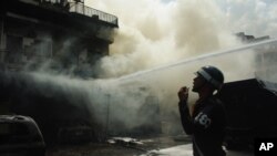 A military police officer stands guard as fire fighters are putting out the blaze. 