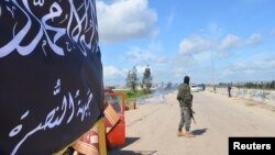 FILE - Members of al-Qaida's Nusra Front man a checkpoint in Idlib.