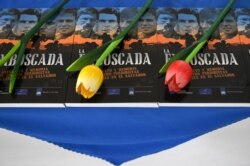 Vista de flores en ejemplares del libro 'La Emboscada' sobre el caso de los cuatro periodistas holandeses asesinados por las Fuerzas Armadas salvadoreñas en el 39 aniversario del crimen, en San Salvador, el 17 de marzo de 2021. ​