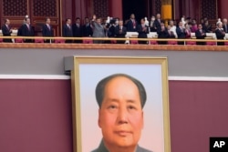 Chinese President Xi Jinping, center, waves above a large portrait of the late leader Mao Zedong during a ceremony to mark the 100th anniversary of the founding of the ruling Chinese Communist Party at Tiananmen Gate in Beijing Thursday, July 1,…