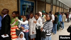 People queue to withdraw cash outside a bank in Harare, Zimbabwe, Nov. 28, 2017.