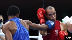 Eldric Sella Rodríguez (rojo) del Equipo Olímpico de Refugiados y Euri Cedeno Martínez de la República Dominicana pelean durante el combate de boxeo preliminar de peso medio masculino (69-75 kg) durante los Juegos Olímpicos de Tokio 2020 en el Kokugikan A