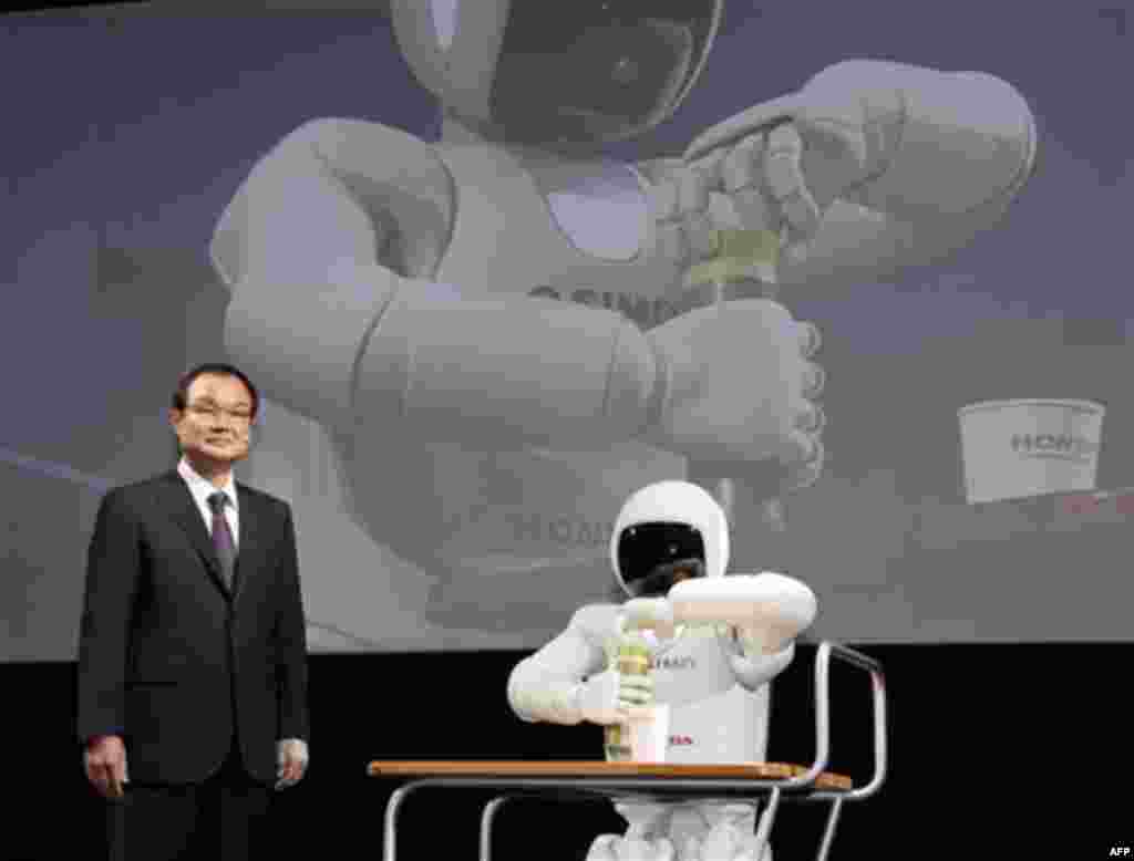 Honda Motor Co. President Takanobu Ito stands near Honda's human-shaped robot "Asimo" at a press conference during the press preview of Tokyo Motor Show in Tokyo, Wednesday, Nov. 30, 2011. The Tokyo Motor Show opens to the public this weekend. (AP Photo/K