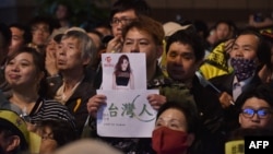 A supporter of Taiwan's Democratic Progressive Party holds up a placard of Chou Tzu-yu, who was forced to apologize after waving the Taiwanese flag