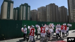 A group of supporters walk holding posters of Mongolian People's Party parliamentary candidate Bat-Amgalan Enkhtaivan on a street in Ulaanbaatar, Mongolia on June 23, 2024, ahead of the parliamentary elections on June 28.