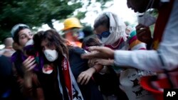 FILE - In this June 11, 2013, photo, a protester affected by tear gas is helped by other protesters to a field hospital in Gezi Park in Taksim Square in Istanbul, Turkey.