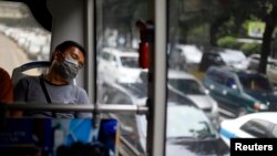 Seorang penumpang tidur di dalam bus Trans Jakarta dengan latar belakang kemacetan jalan raya Jakarta.(Reuters/Beawiharta)