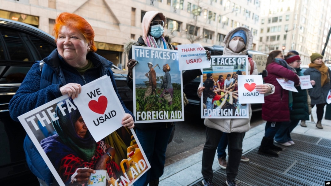 Penzionisana radnica Agencije Sjedinjenih Američkih Država za međunarodni razvoj Julie Hanson Swanson, lijevo, pridružuje se pristalicama radnika USAID-a ispred Ureda USAID-ovog Biroa za humanitarna pitanja u Washingtonu, 21. februara 2025.