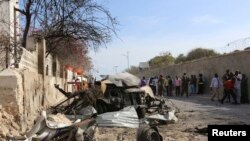 People look at the scene of a suicide attack next to the gate of the Presidential Palace in Mogadishu February 21, 2014. Al Qaeda-linked militants al Shabaab attacked the Somali presidential palace compound on Friday, blasting through a gate with a car bo