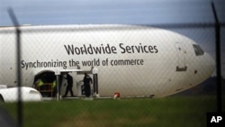 Investigators are seen with a United Parcel Service jet near the company's facility at Philadelphia International Airport, Friday, Oct. 29, 2010.