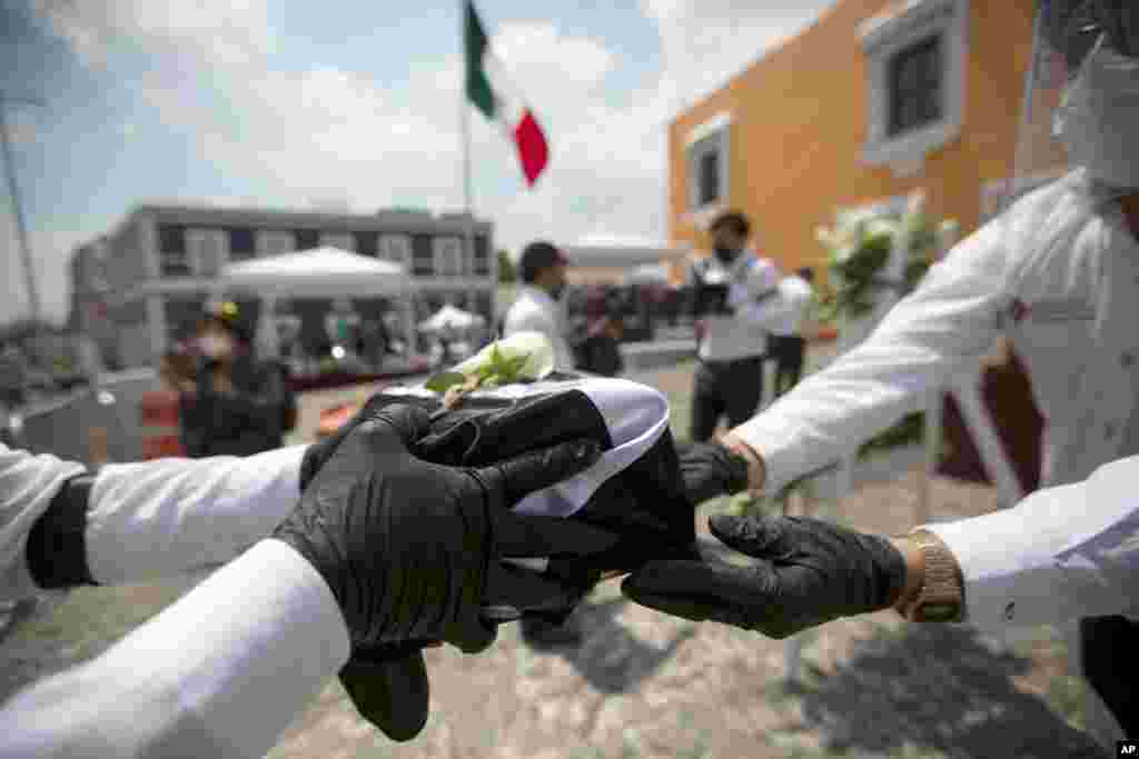 State workers handle an urn holding the ashes of a Mexican citizen who died in the U.S. from COVID-19 complications, during a ceremony in Puebla, Mexico, July 13, 2020. The remains of 105 Mexicans were returned to their families.
