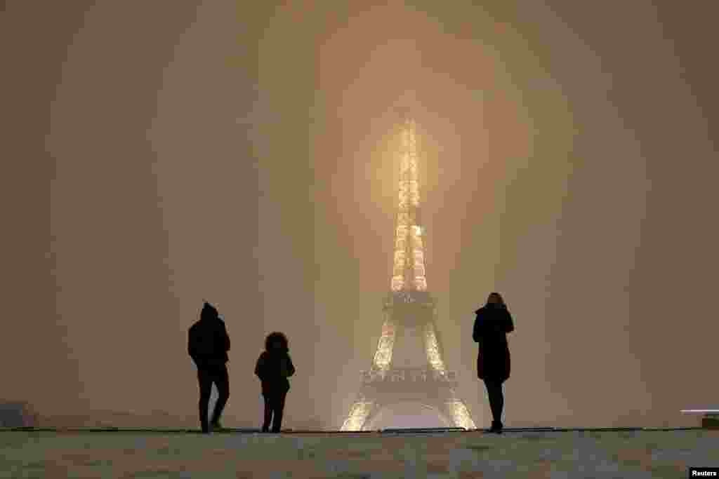 Tourists walk on a snow-covered path near the Eiffel Tower in Paris, as winter weather with snow and freezing temperatures arrive in France, Feb. 6, 2018.