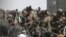Tentara AS berjaga di balik kawat berduri saat warga Afghanistan duduk di pinggir jalan dekat bagian militer bandara di Kabul, 20 Agustus 2021.(Foto: AFP)