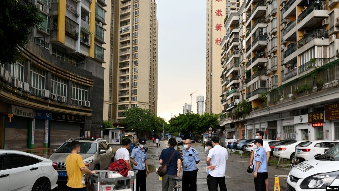 Police officers speak to people behind a police line near a residential area 