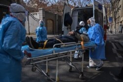 FILE - Medical staff in protective clothing transport a suspected coronavirus patient from an apartment in Wuhan, Hubei province, China, Jan. 30, 2020.