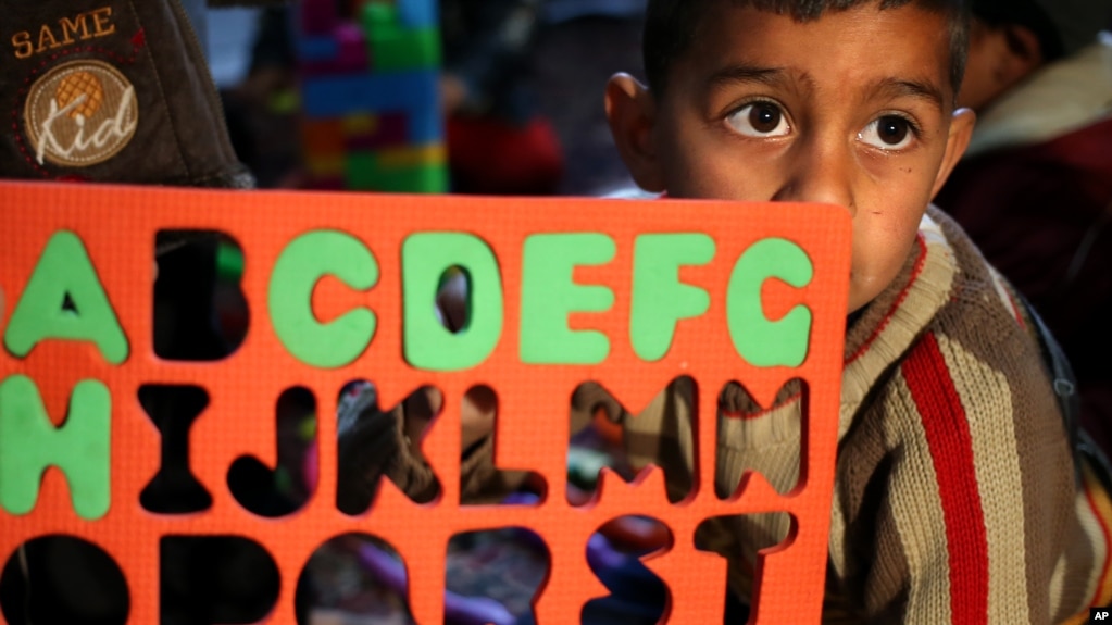 FILE - In this picture taken on Wednesday, March 12, 2014, a Syrian refugee boy Saleh el-Hussein, 5, looks on as he follows a lesson about the English alphabets. (AP Photo/Hussein Malla)