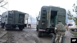 Ukrainian soldiers load the surviving equipment at a destroyed Ukrainian military facility outside Mariupol, Ukraine, Feb. 24, 2022. Russia has launched a barrage of air and missile strikes on Ukraine early Thursday and Ukrainian officials said that Russi