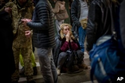 A woman reacts as she waits for a train trying to leave Kyiv, Ukraine, after Russian troops launched their anticipated attack on the country Feb. 24, 2022. (AP Photo/Emilio Morenatti)