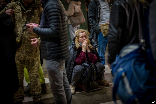 A woman reacts as she waits for a train trying to leave Kyiv, Ukraine, after Russian troops launched their anticipated attack on the country Feb. 24, 2022. (AP Photo/Emilio Morenatti)
