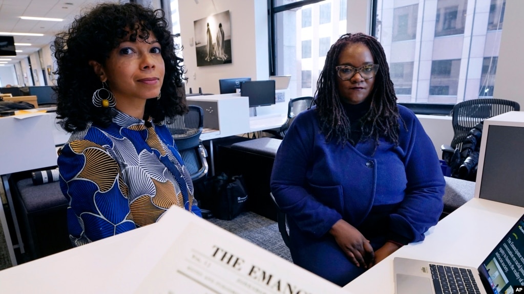 Amber Payne, left, and Deborah Douglas co-editors-in-chief of the new online publication of "The Emancipator" pose at their office inside the Boston Globe, Feb. 2, 2022, in Boston. (AP Photo/Charles Krupa)