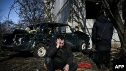 Un homme est assis à l'extérieur de son bâtiment détruit après les bombardements sur la ville de Chuguiv, dans l'est de l'Ukraine, le 24 février 2022.