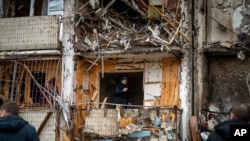 A man inspects the damage at a building following a rocket attack on the city of Kyiv, Ukraine, Feb. 25, 2022.