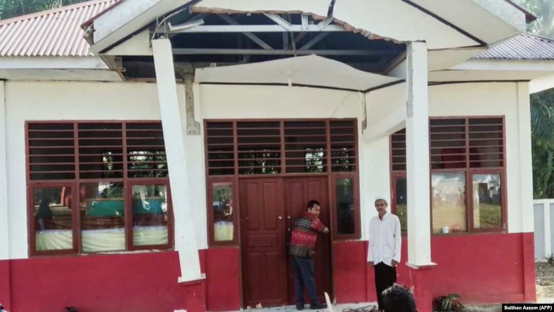 Warga memeriksa bangunan yang rusak akibat gempa 6,2 SR di Desa Kajai, Pasaman Barat, 25 Februari 2022. (Foto: AFP/Sulthan Azzam)