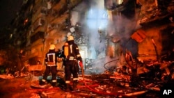 In this handout photo taken from video released by Ukrainian Police Department Press Service, firefighters inspect the damage at a building following a rocket attack on the city of Kyiv, Ukraine, Feb. 25, 2022.