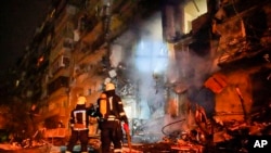 In this handout photo taken from video released by Ukrainian Police Department Press Service, firefighters inspect the damage at a building following a rocket attack on the city of Kyiv, Ukraine, Feb. 25, 2022.