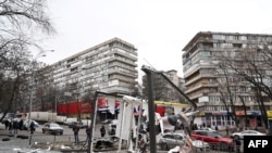 People are seen outside the cordoned-off area around the remains of a shell in a street in Kyiv, Feb. 24, 2022. Russian President Vladimir Putin announced a military operation in Ukraine on Thursday.