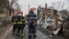 Bombeiros olham resultado de um ataque na área de Kiev