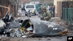 A Ukrainian Army soldier inspects fragments of a downed aircraft in Kyiv, Ukraine, Friday, Feb. 25, 2022. It was unclear what aircraft crashed and what brought it down amid the Russian invasion in Ukraine. (AP Photo/Vadim Zamirovsky)
