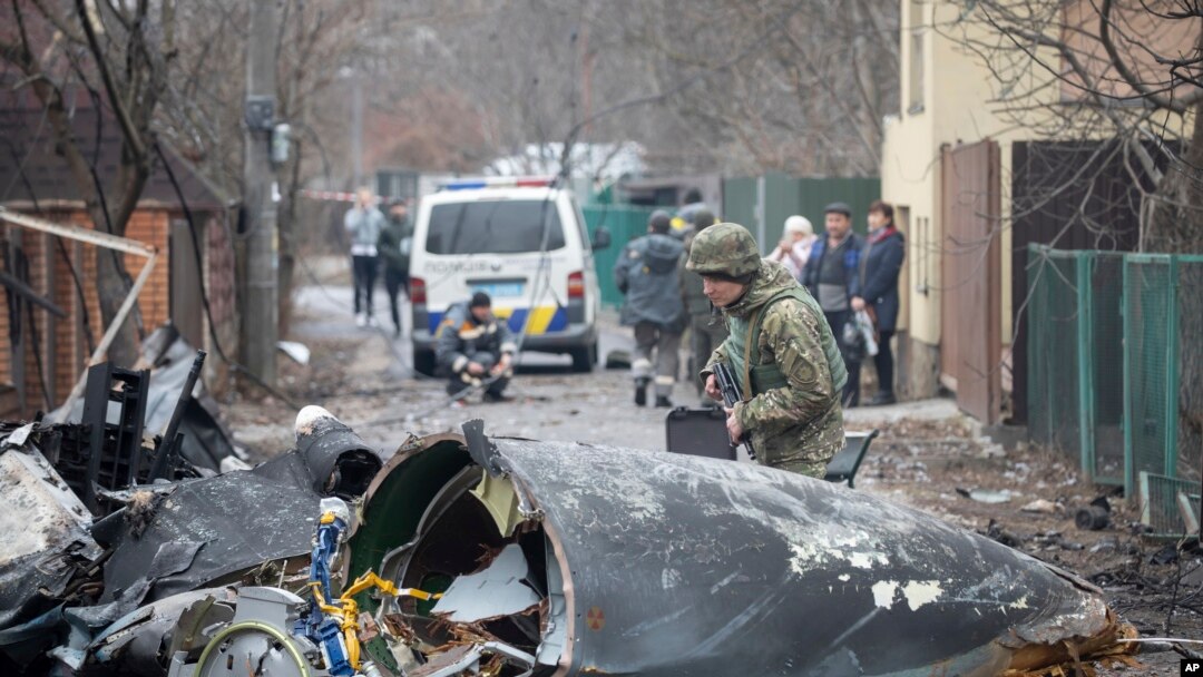 Seorang prajurit Angkatan Darat Ukraina memeriksa pecahan pesawat yang jatuh di Kyiv, Ukraina, Jumat, 25 Februari 2022. (Foto: AP)