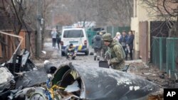 Seorang prajurit Angkatan Darat Ukraina memeriksa pecahan pesawat yang jatuh di Kyiv, Ukraina, Jumat, 25 Februari 2022. (Foto: AP)