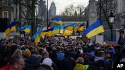 People hold placards and Ukrainian flags as they attend a demonstration in support of Ukraine, outside Downing Street, in London, Feb. 24, 2022.